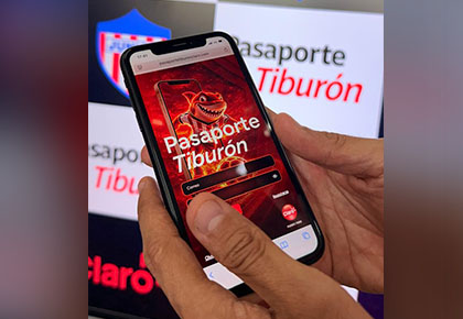 Usuario accede a Pasaporte Tiburón desde su celular junto al escudo del Junior FC